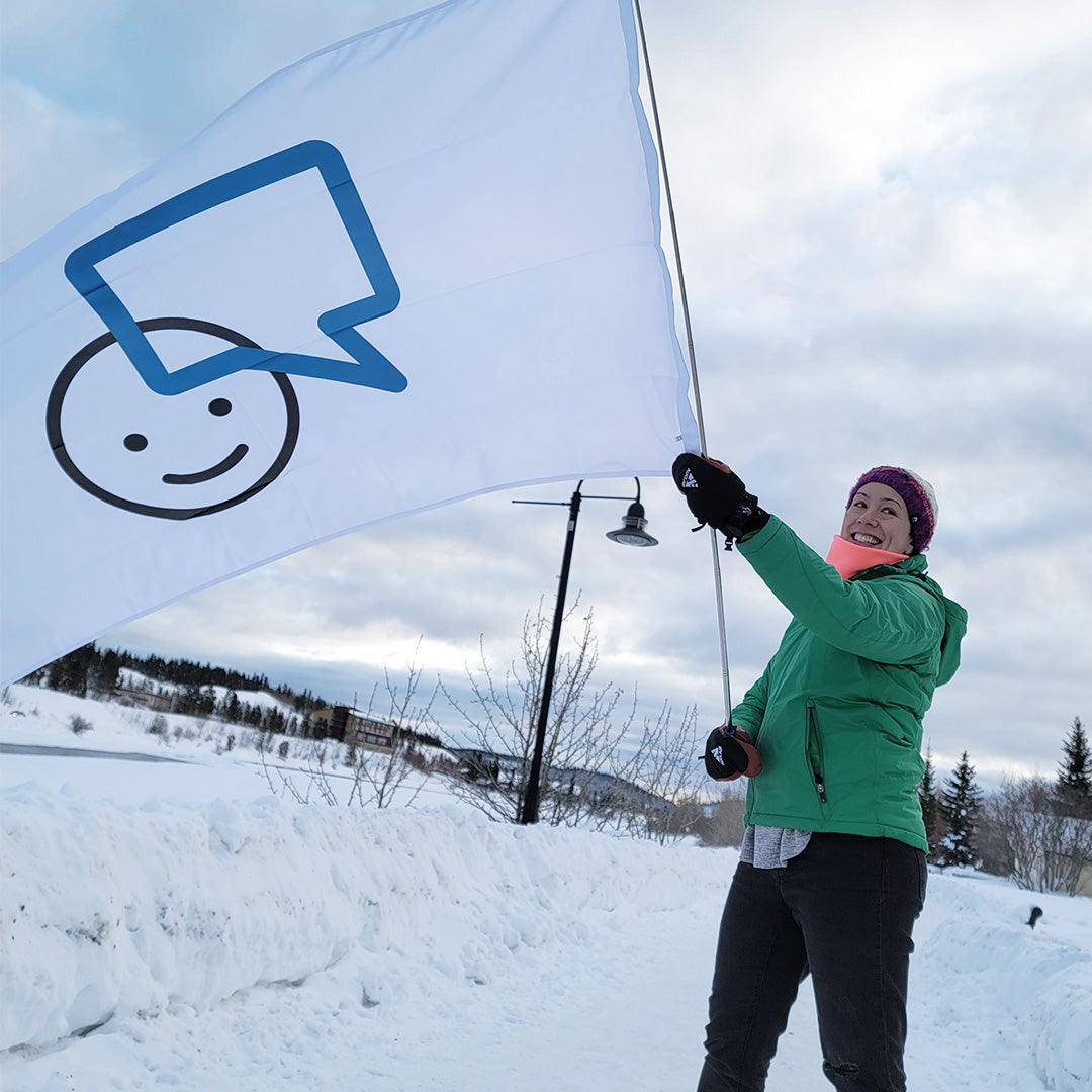 Andrea waving the Bell Let's Talk Day flag in the Yukon