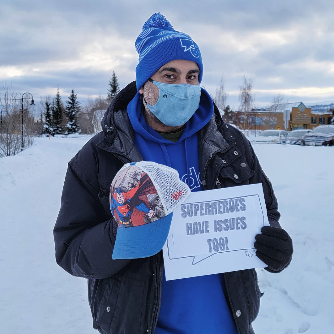 Sunny holding up a Bell Let's Talk sign with "Super heroes have issues too" in Yukon