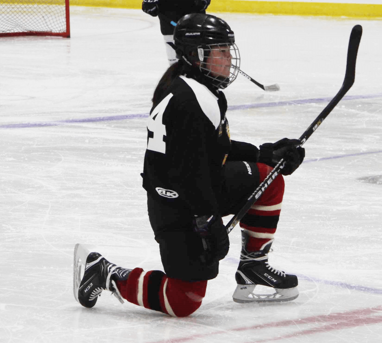 Female hockey player kneeling on ice