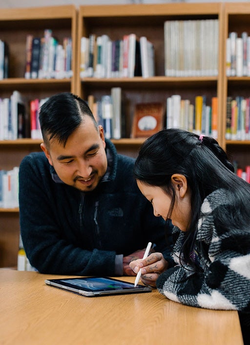 Brian Kowikchuk and his niece, sitting at a table doing art on an ipad.