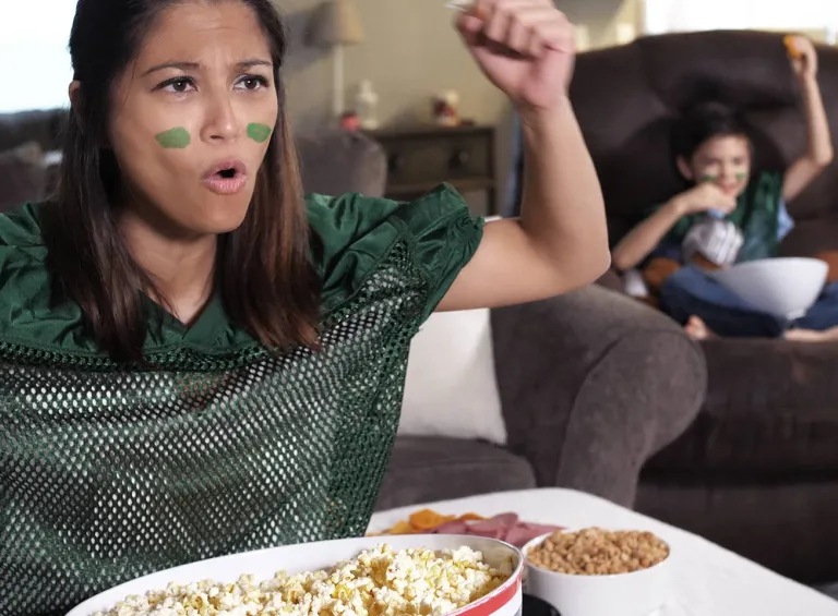 A woman and her child cheering their team from the couch