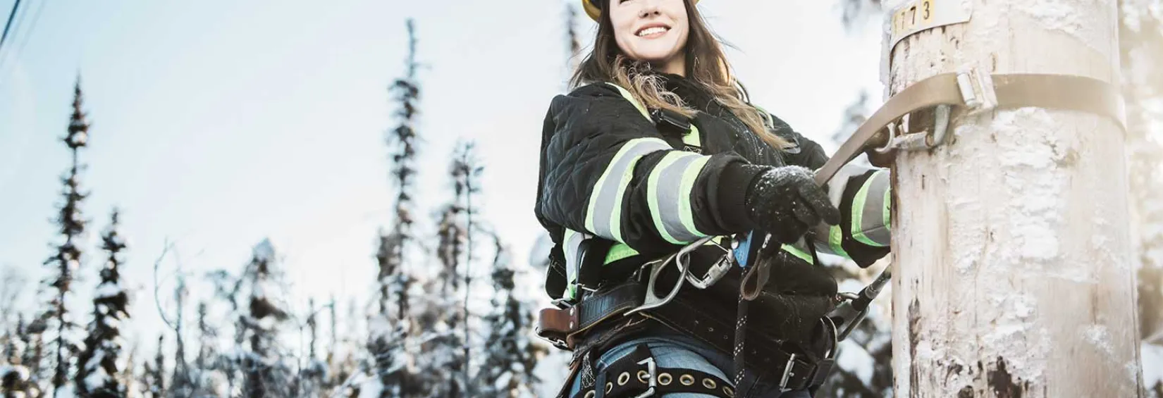 Service technician Nicole climbing a pole in a snowed northern background