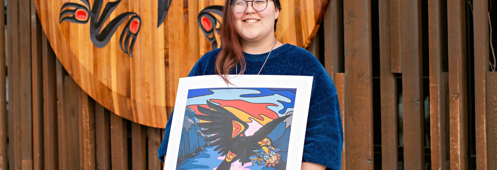 Kayla Smith-Clarke with the Crow and the Native Spirit Kayla Smith-Clarke standing with her digital directory art winner, the Crow and the Native Spirit