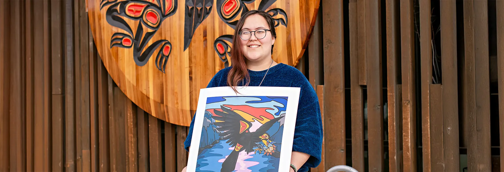 Kayla Smith-Clarke standing with her digital directory art winner, the Crow and the Native Spirit